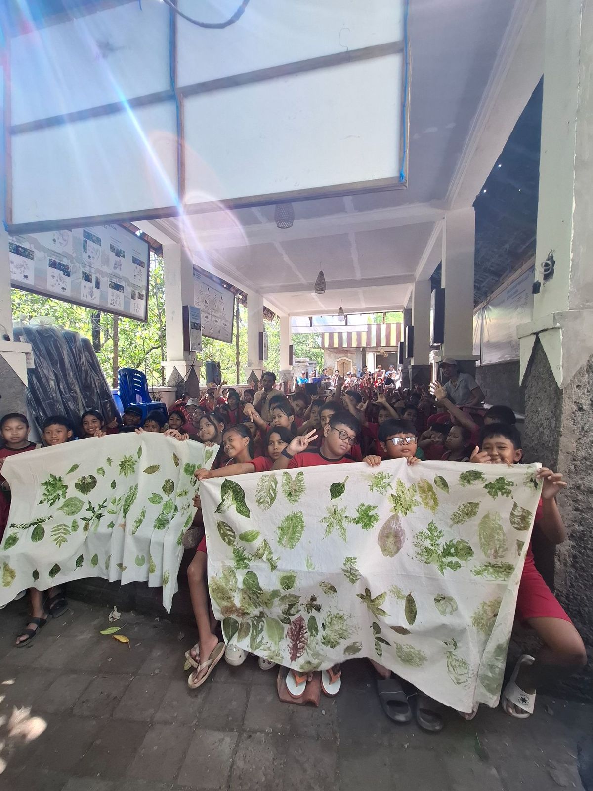 Participants showing fabrics decorated with mangrove leaves in an ecoprint workshop